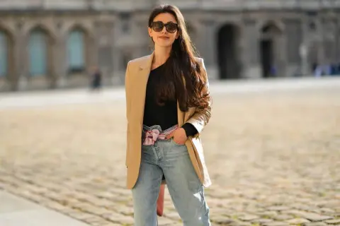 Stylowa kobieta w beżowej marynarce i jeansach mom fit. Jej stylizacje to kwintesencja miejskiego szyku.