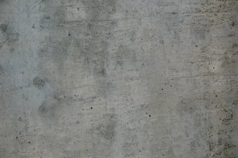 Szara, chropowata powierzchnia betonu z widocznymi nierównościami i śladami po szalunku.