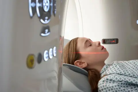 Mädchen in CT-Scanner, rote Laserlinien zur Positionierung für die Untersuchung, um einen ct tumor erkennen zu können.