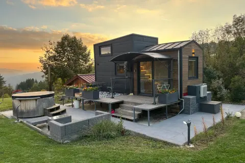 Tiny house dans le Jura, avec jacuzzi et mobilier extérieur, au coucher du soleil.