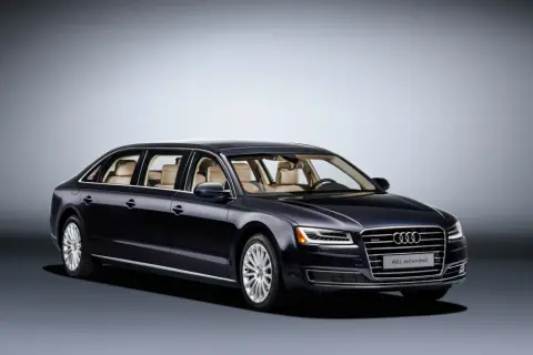 Ciemnogranatowy Audi A8L extended, luksusowa limuzyna z jasnym wnętrzem, prezentuje się elegancko na tle gradientu.
