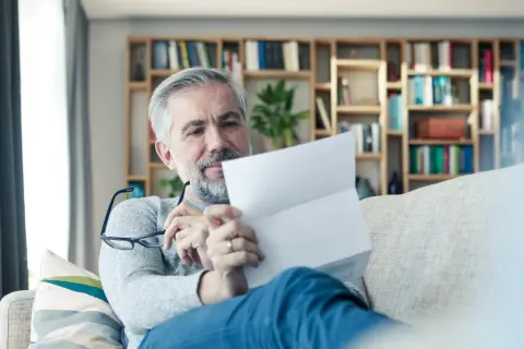 Mężczyzna z siwą brodą czyta dokumenty, szukając informacji o przerwie w OC, jak uniknąć kary.