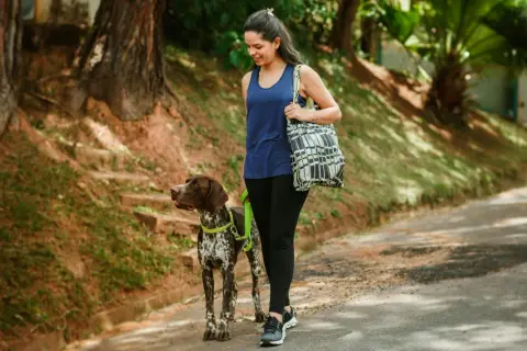 Frau geht mit Hund spazieren, ein toller Weg, um den Kalorienverbrauch beim Spazierengehen zu steigern und die Natur zu genießen.
