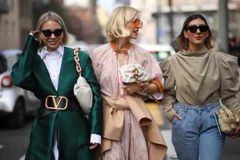 Tre donne sfoggiano un outfit pasqua alla moda: giacca verde smeraldo, abito floreale e top beige con jeans.