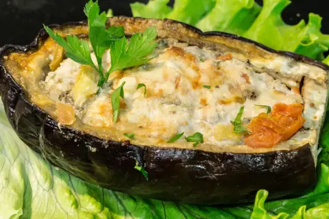 Melanzane ripiene di carne al forno, un piatto gustoso e colorato, servito su un letto di lattuga fresca.