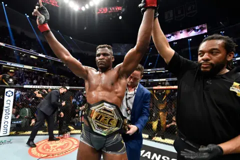 En segerrik UFC-mästare, med bälte och armarna i luften, firar som en riktig sumo brottare.