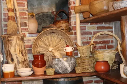Vasi in terracotta, cesti intrecciati e scope di paglia evocano antiche attività artigianali.