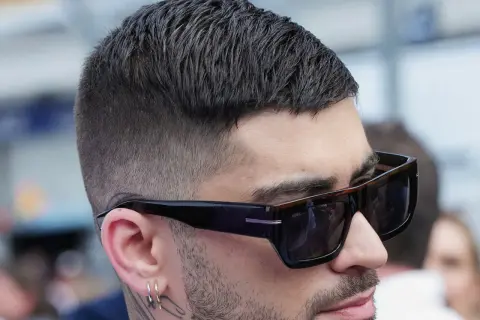 Nahaufnahme eines Mannes mit kurz geschnittenem, dunklem Haar und Sonnenbrille. Sein moderner herren haarschnitt ist perfekt gestylt.