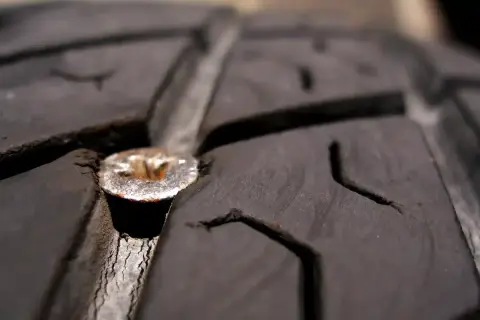 Une mèche est plantée dans le pneu d'une voiture, causant une crevaison.