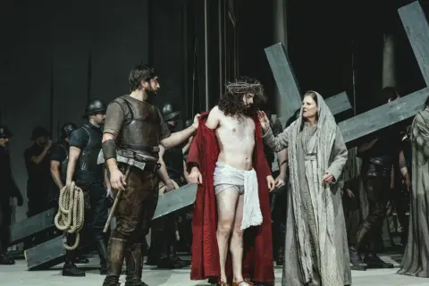 Szene aus einem Passionsspiel: Jesus mit Dornenkrone, umgeben von Soldaten und Frauen, die ein Kreuz tragen.