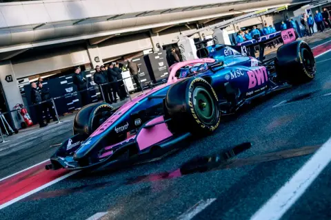 Coche de **Alpine F1** azul y rosa listo para la carrera en el pit lane.