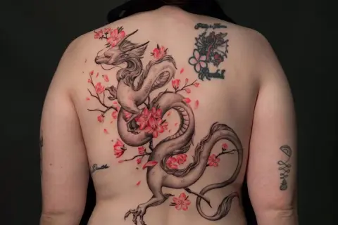 Dragón oriental entre flores de cerezo, un diseño de tatuajes ornamentales que evoca fuerza y belleza.