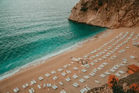 Piękna plaża z rzędami leżaków i turkusową wodą. Idealne miejsce, by zastanowić się, gdzie do Turcji na wakacje.