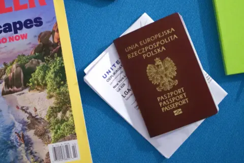 Polski paszport i bilet lotniczy na podróż do Kanady. Obok magazyn podróżniczy i zielony notatnik.