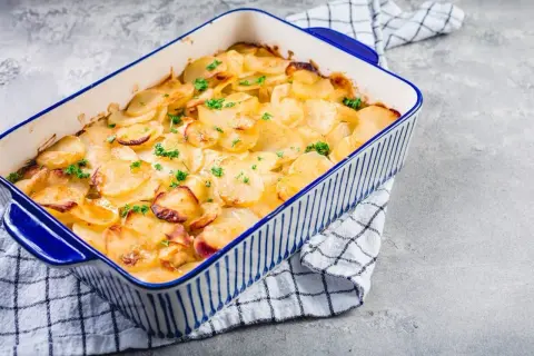 Goldbrauner Kartoffelauflauf mit Petersilie in einer blauen Auflaufform. Ein köstliches Kartoffelauflauf Rezept, das zum Genießen einlädt.