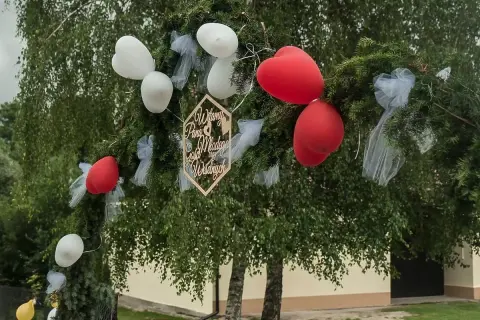 Brama weselna z gałęzi i balonów, ozdobiona drewnianym napisem "Witamy Parę Młodą". Wierszyki na ślub to piękna tradycja.