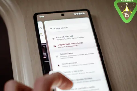 Mano interactuando con un teléfono que muestra la configuración de Android 15. El logo de Android 15 aparece en la esquina superior derecha.