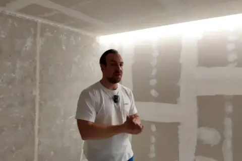 Mężczyzna prezentuje wnękę na led w suficie, która tworzy nowoczesne oświetlenie.