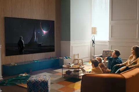 Familj tittar på en rymdfilm på TV:n, sittandes bekvämt i soffan. Avstånd tv soffa är perfekt för en mysig hemmakväll.