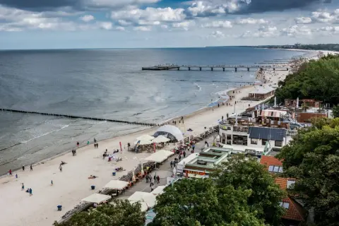 Plaża nad Bałtykiem, molo, restauracje i spacerowicze. Idealne miejsce na tanie wczasy we wrześniu w Polsce.