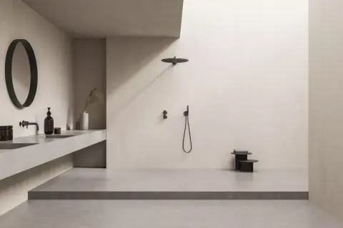 Minimalistisches Bad mit offener Dusche. Die bodentiefe Dusche ist so gestaltet, dass Spritzwasser vermieden wird. Ein runder Spiegel und ein schwebendes Waschbecken ergänzen den Look.