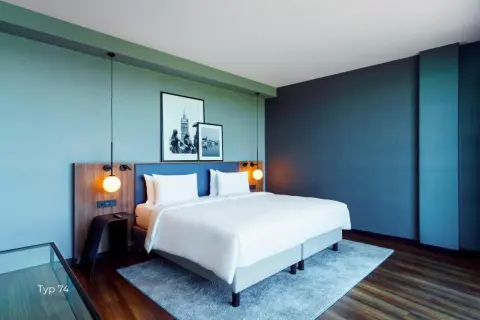 Nowoczesny pokój w **Radisson Blu Hotel Rostock** z wygodnym łóżkiem, dwoma obrazami na ścianie i stylowymi lampami.