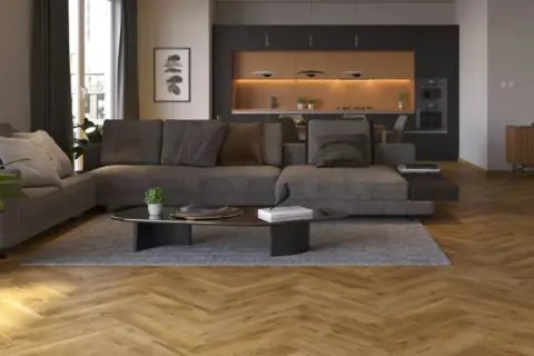 Nowoczesny salon z szarą sofą i ciemną ścianą w tle, za którą widać kuchnię.