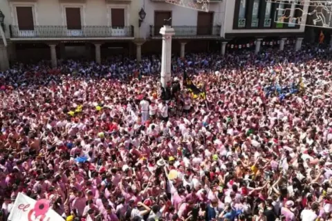Multitudinaria plaza en las fiestas del Torico de Teruel, con gente vestida de blanco y rosa celebrando.