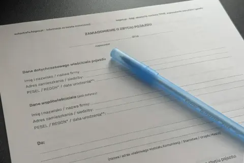 Formularz "Zawiadomienie o zbyciu pojazdu" z niebieskim długopisem. Dokument zawiera pola do wpisania danych poprzedniego właściciela i współwłaściciela pojazdu.