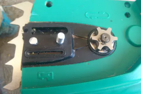 Widok z bliska na mechanizm piły elektrycznej, w tym zębatkę i elementy pompki oleju.