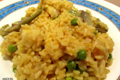 Arroz con bacalao y alcachofas, un plato reconfortante con guisantes verdes y trozos de pescado blanco.
