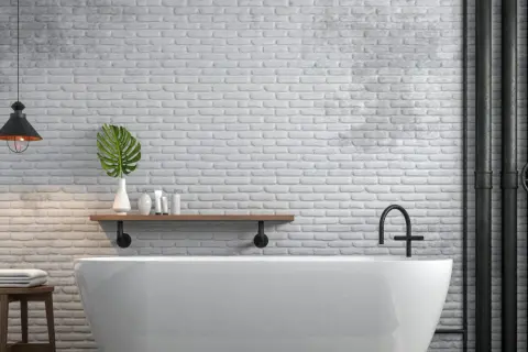 Bagno moderno con vasca bianca, mattoni a vista e tubi industriali neri. Ottime idee per coprire tubi a vista con stile.