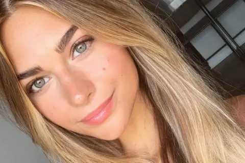 Uśmiechnięta dziewczyna z zielonymi oczami i włosami w odcieniu sombre blond.