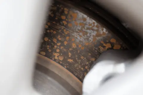 Närbild på rostiga bromsskivor med orange fläckar som vittnar om tidens tand.