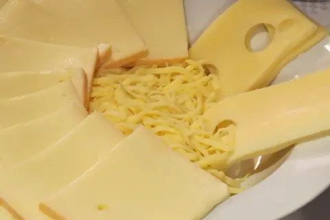 Assiette de fromages variés, dont des tranches d'Emmental avec ses trous caractéristiques, et du Gruyère râpé. La différence entre gruyère et emmental est subtile.