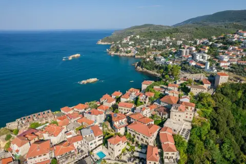 Widok na malownicze miasteczko Ulcinj z czerwonymi dachami, otoczone zielonymi wzgórzami i błękitnym morzem. Odkryj atrakcje tego nadmorskiego kurortu.