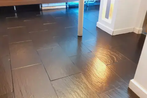 Pavimento in bollettonato di marmo scuro, lucido e riflettente, con un pilastro bianco al centro.