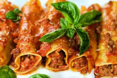 Cannelloni di carne ricetta della nonna, ripieni di ragù e conditi con sugo rosso e basilico fresco. Un piatto che sa di casa.