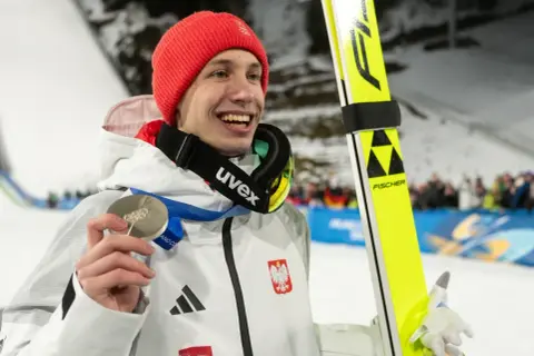 Uśmiechnięty skoczek narciarski w czerwonej czapce trzyma srebrny medal. Czy za dwa medale olimpijskie są dwie emerytury?
