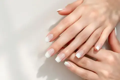 Mains délicates aux ongles parfaits, arborant une manucure blanche classique et élégante.