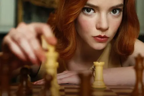 Anya Taylor-Joy jako Beth Harmon w "Gambicie Królowej" przygotowuje ruch na szachownicy.