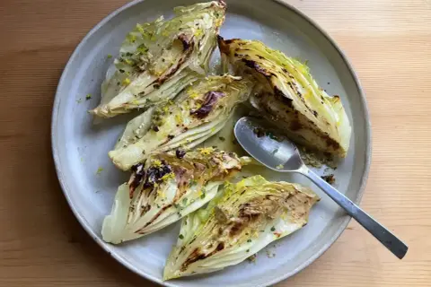 Grilla spetskål med citron och örter, serverad på en ljusgrå tallrik med en sked.