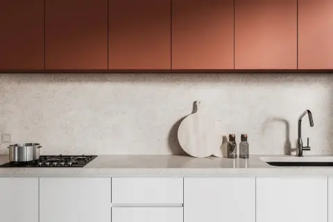 Crédence derrière plaque de cuisson gaz, avec un plan de travail en marbre clair, des placards cuivrés et un évier moderne.