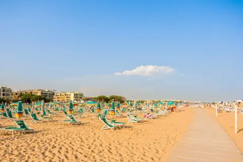 Piękna plaża w Bibione, pełna leżaków i parasoli, zaprasza do relaksu. Liczne atrakcje czekają na turystów.