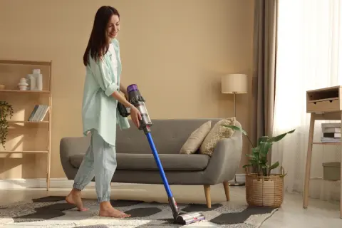 Kobieta sprząta salon odkurzaczem Dyson.