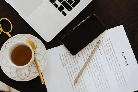 Złote nożyczki, filiżanka kawy i telefon leżą obok umowy. Gdzie zgłosić nabycie nieruchomości? Sprawdź warunki umowy.