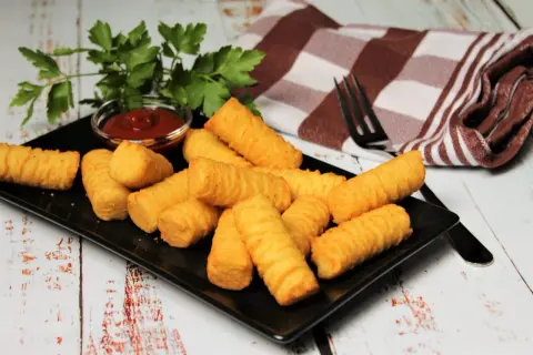 Goldbraune Kroketten, frisch zubereitet, liegen auf einem schwarzen Teller. Dazu gibt es Ketchup und frische Petersilie. Perfekt zum selber machen!