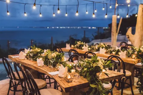 Tavoli apparecchiati per un magico matrimonio di sera, con luci soffuse e vista sul mare.