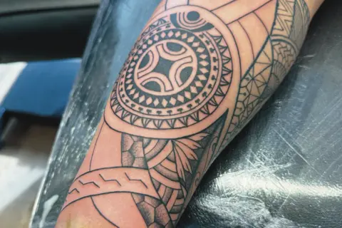 Ein detailliertes Maori-Tattoo auf dem Arm, das die Verbundenheit der Familie symbolisiert.