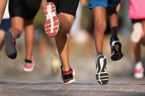 Des coureurs en action, leurs jambes et chaussures en mouvement. Une scène dynamique pour apprendre à courir.